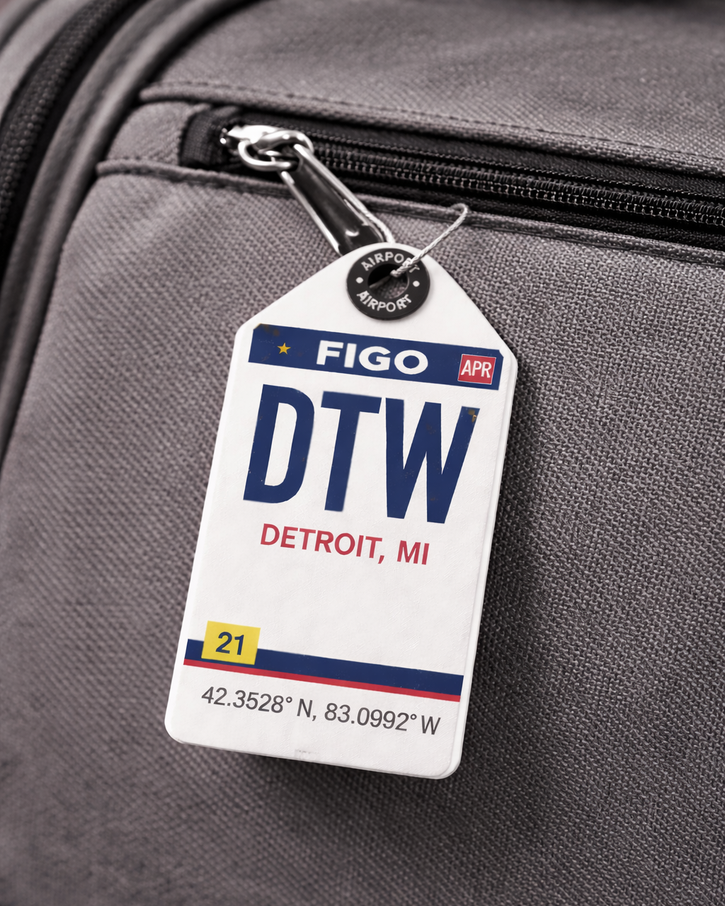 Luggage tag with 'DTW' and 'Detroit, MI' on a gray suitcase